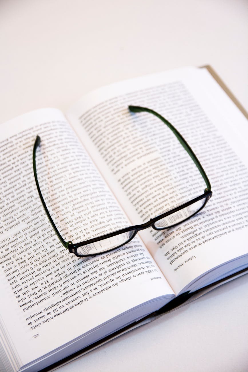 Open book with eyeglasses resting on pages, symbolizing reading and knowledge.